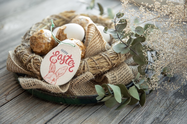 Easter composition with decorated Easter eggs and decorative nest on a wooden surface